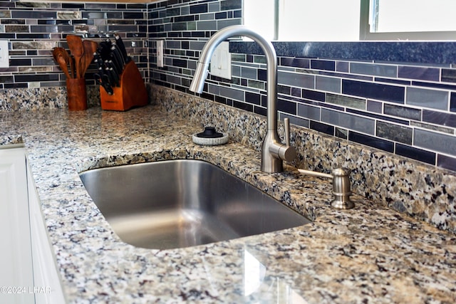 details with tasteful backsplash, sink, and stone countertops