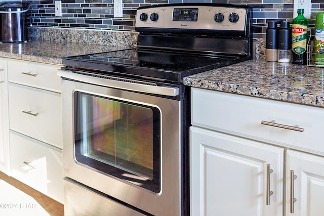 kitchen with stone counters, white cabinets, decorative backsplash, and electric range