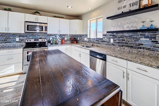 kitchen featuring white cabinetry, stainless steel appliances, sink, and dark stone countertops