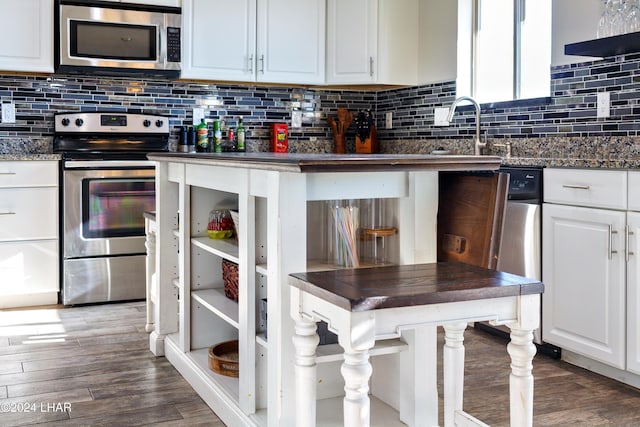 kitchen featuring appliances with stainless steel finishes, dark hardwood / wood-style floors, white cabinets, and backsplash