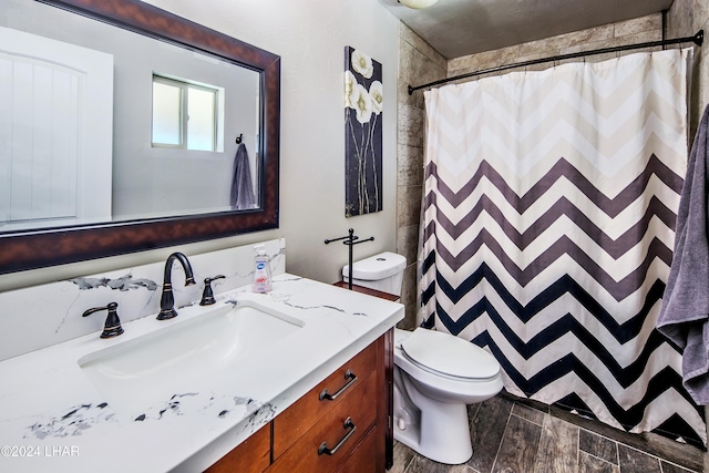 bathroom featuring vanity, toilet, and walk in shower