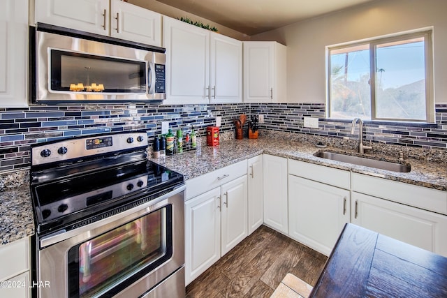 kitchen featuring sink, appliances with stainless steel finishes, white cabinets, decorative backsplash, and dark stone counters