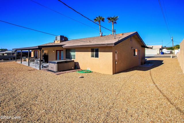 rear view of house with a hot tub and a patio