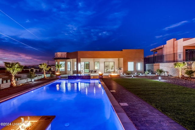 pool at dusk with a patio and a lawn