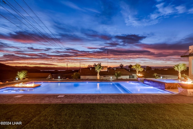 pool at dusk featuring an in ground hot tub