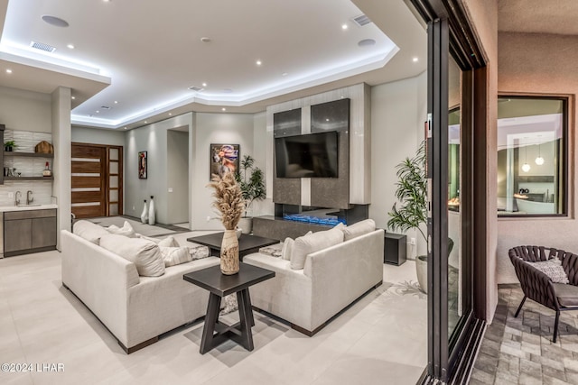 living room featuring sink, a fireplace, and a raised ceiling