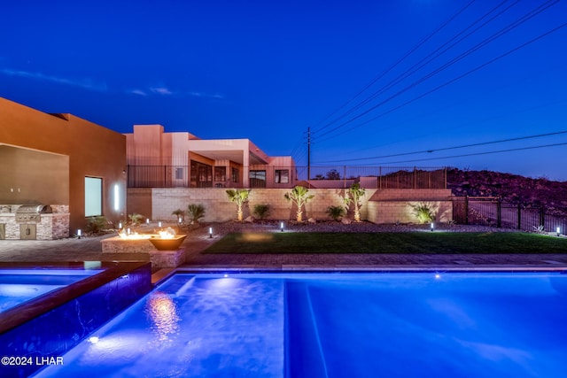 view of pool featuring pool water feature, area for grilling, and a fire pit