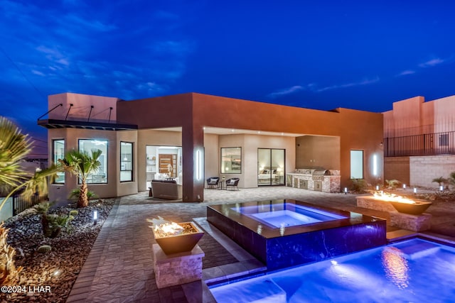 back house at dusk featuring a swimming pool with hot tub, area for grilling, a patio area, and an outdoor fire pit