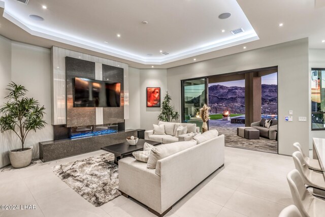 living room with light tile patterned floors and a tray ceiling