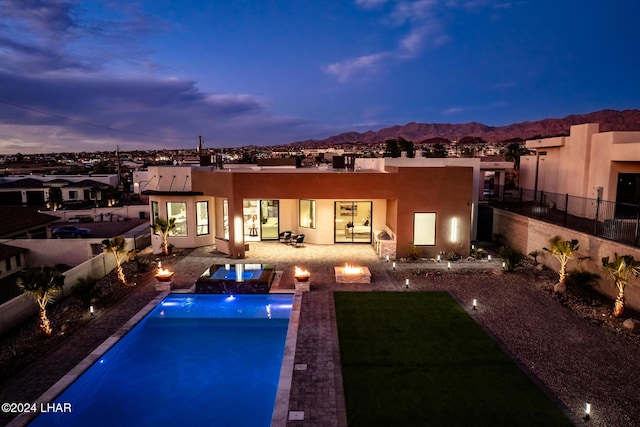 back house at dusk featuring a mountain view, a fire pit, and a patio