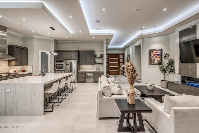 living room with light tile patterned flooring, a tray ceiling, and beverage cooler