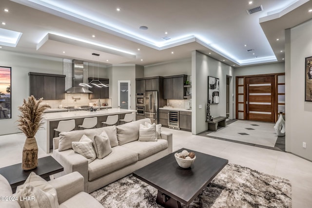 tiled living room with a skylight, beverage cooler, a raised ceiling, and sink