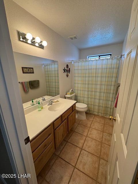 bathroom with vanity, visible vents, a textured ceiling, tile patterned floors, and toilet