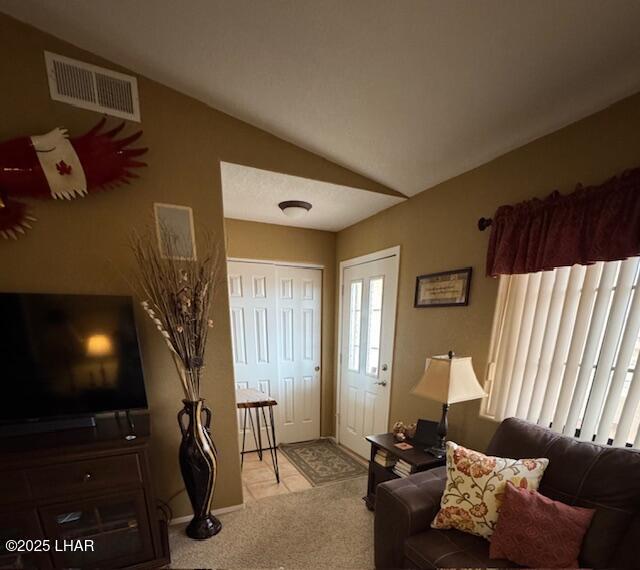 carpeted living room featuring visible vents and vaulted ceiling