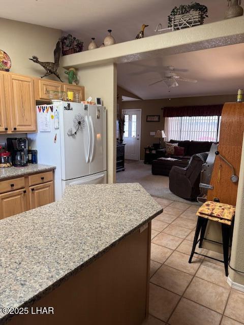 kitchen featuring light brown cabinets, vaulted ceiling, light tile patterned floors, freestanding refrigerator, and a ceiling fan