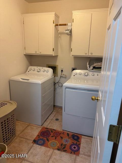 laundry area featuring washer and clothes dryer, light tile patterned floors, and cabinet space