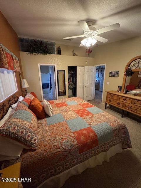 carpeted bedroom featuring ceiling fan, a closet, ensuite bathroom, and a textured ceiling