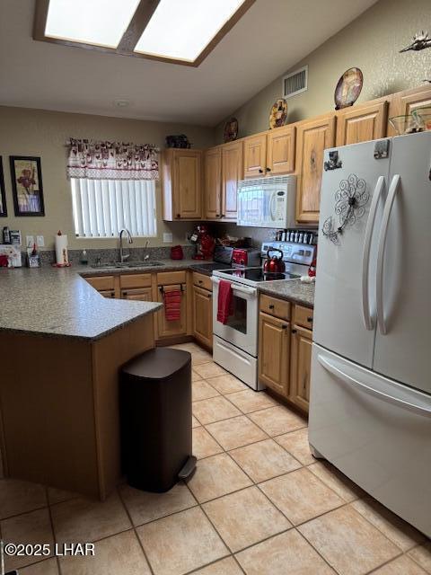 kitchen with visible vents, vaulted ceiling, light tile patterned floors, white appliances, and a sink