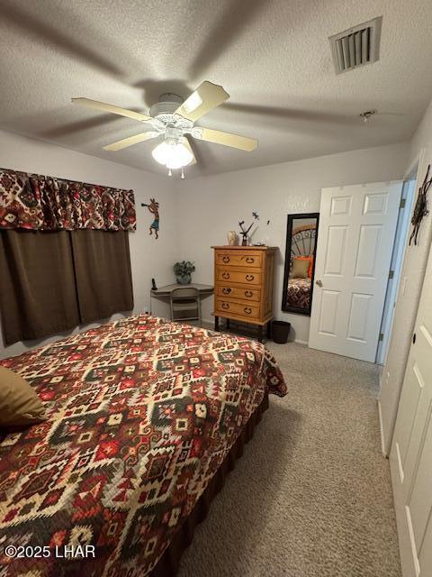 carpeted bedroom featuring visible vents, a textured ceiling, and a ceiling fan