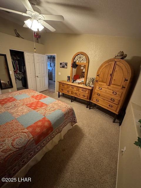 bedroom with a closet, light colored carpet, a ceiling fan, and a textured ceiling