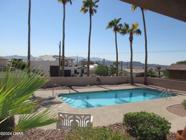 pool featuring a patio area, a fenced backyard, and a mountain view