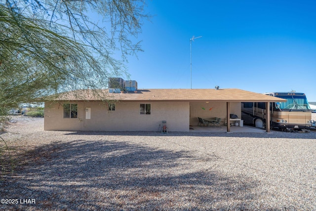 rear view of house featuring stucco siding