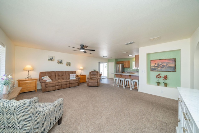 living area with visible vents, carpet floors, and ceiling fan