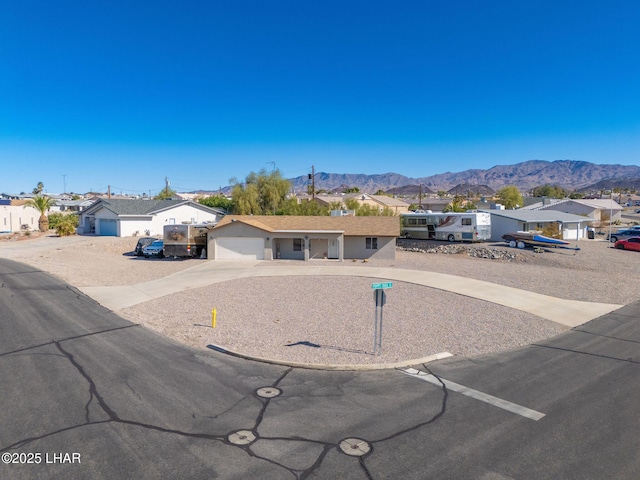 ranch-style home featuring a mountain view, a residential view, a garage, and driveway