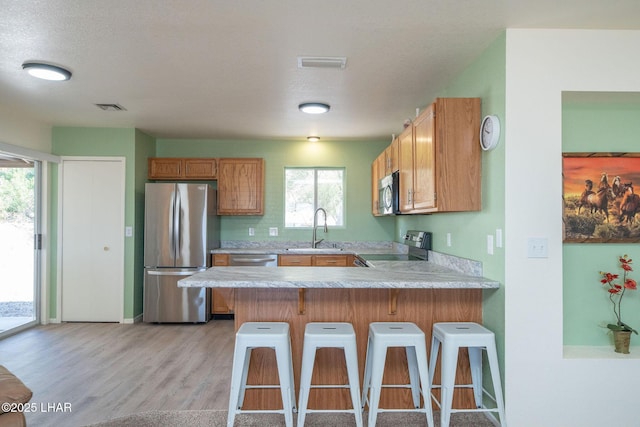 kitchen with visible vents, light countertops, a peninsula, stainless steel appliances, and a sink