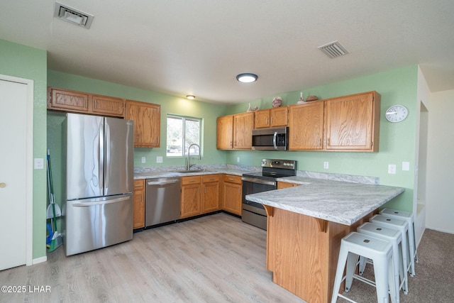 kitchen with visible vents, light countertops, appliances with stainless steel finishes, a peninsula, and a sink