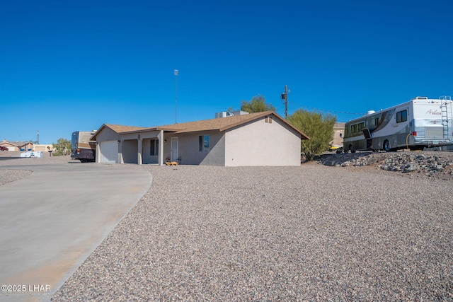 ranch-style home with stucco siding, an attached garage, and driveway