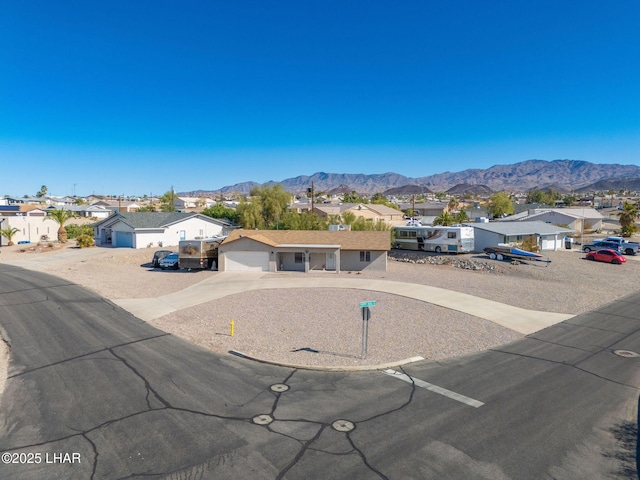 ranch-style home featuring a mountain view, a residential view, an attached garage, and driveway