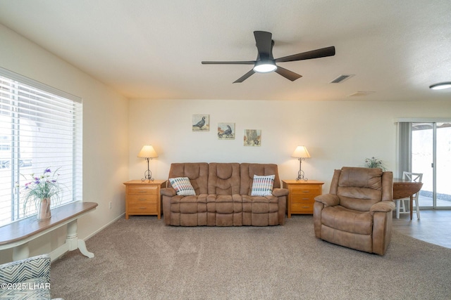 living area with visible vents, carpet floors, baseboards, and a ceiling fan