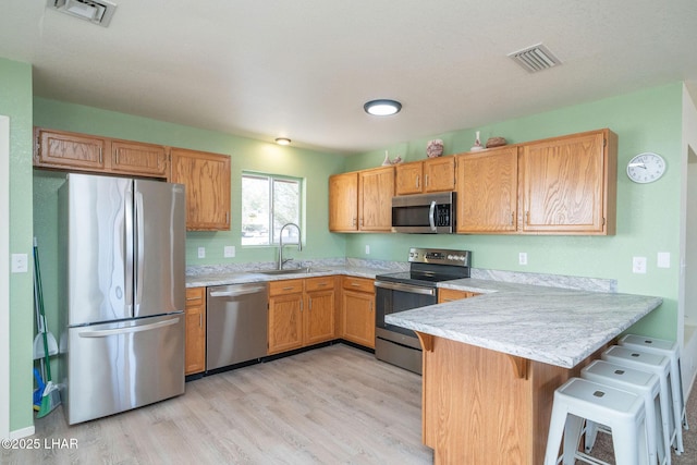 kitchen featuring visible vents, appliances with stainless steel finishes, a peninsula, and a sink