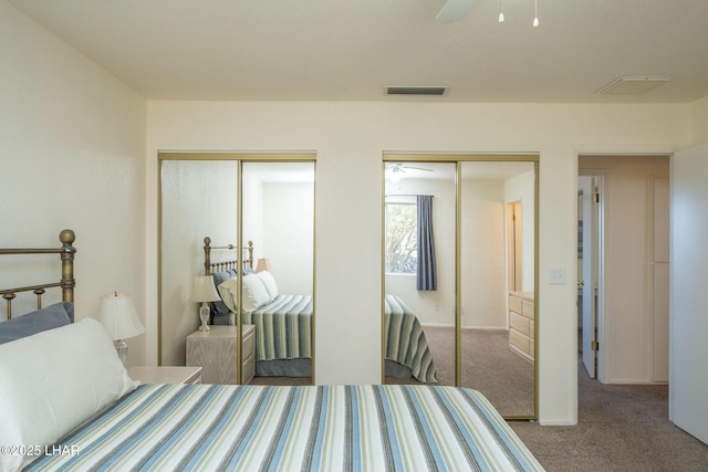 carpeted bedroom featuring visible vents, two closets, and a ceiling fan