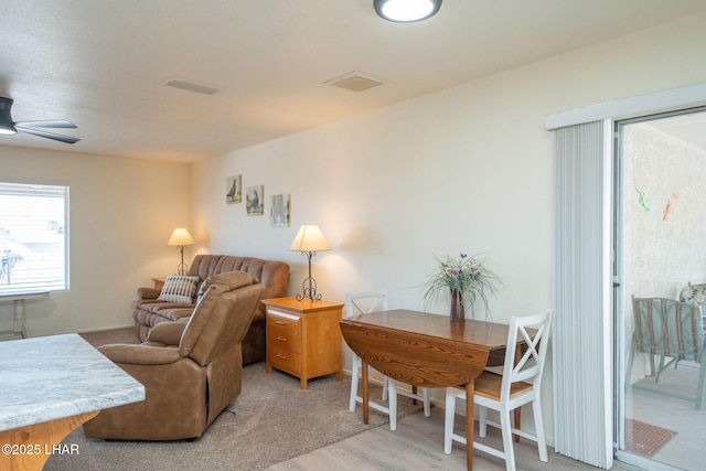 living room featuring a ceiling fan, visible vents, and light wood finished floors