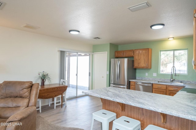 kitchen with a breakfast bar area, a healthy amount of sunlight, visible vents, a peninsula, and stainless steel appliances