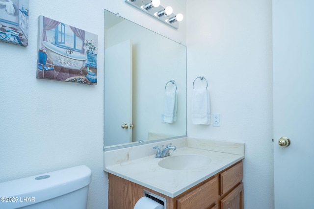 half bath featuring vanity and toilet