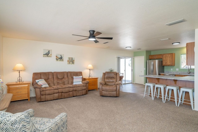 living area featuring a ceiling fan, visible vents, and carpet floors