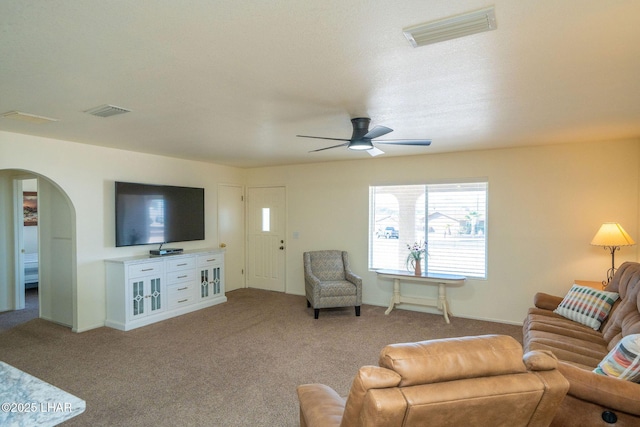 living room featuring arched walkways, visible vents, carpet flooring, and ceiling fan