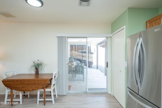 kitchen featuring light wood finished floors, visible vents, and freestanding refrigerator