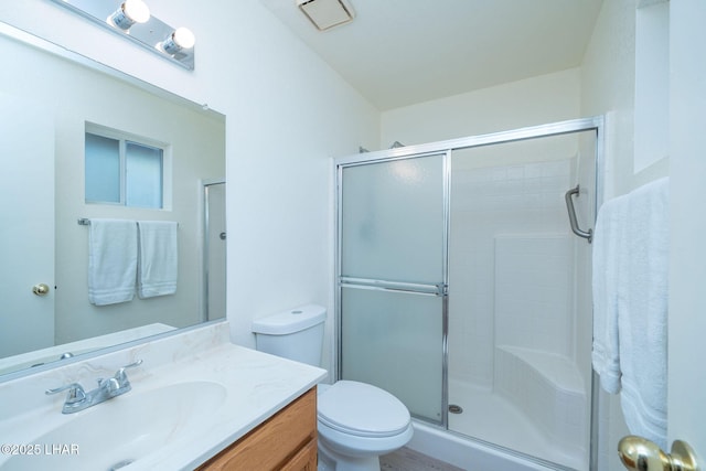 full bath with toilet, vanity, and a shower with shower door