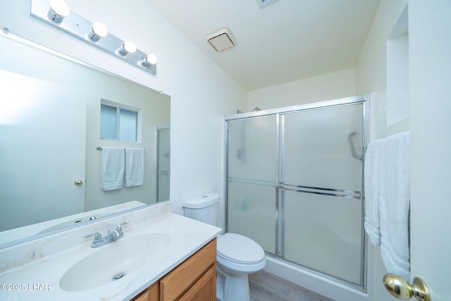 bathroom with a shower with shower door, toilet, and vanity