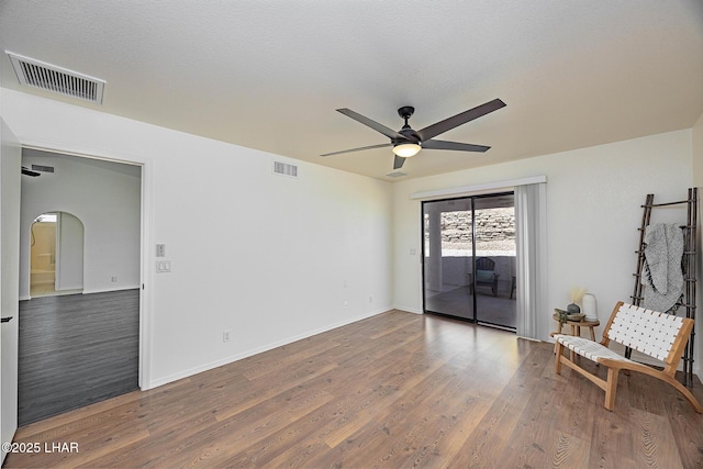 sitting room featuring arched walkways, visible vents, wood finished floors, and ceiling fan