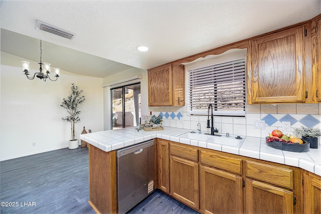 kitchen featuring visible vents, dishwasher, a sink, a peninsula, and brown cabinets