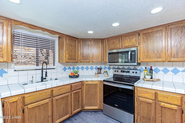 kitchen featuring stainless steel appliances, tasteful backsplash, dark wood-style floors, and a sink