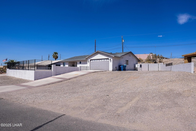 ranch-style home featuring concrete driveway, an attached garage, stucco siding, and a fenced front yard