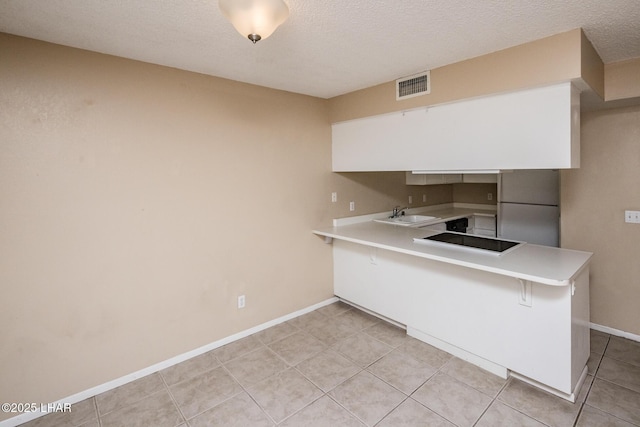 kitchen with sink, refrigerator, kitchen peninsula, black electric stovetop, and white cabinets