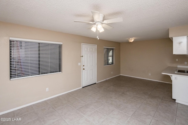 interior space featuring light tile patterned floors, a textured ceiling, and ceiling fan