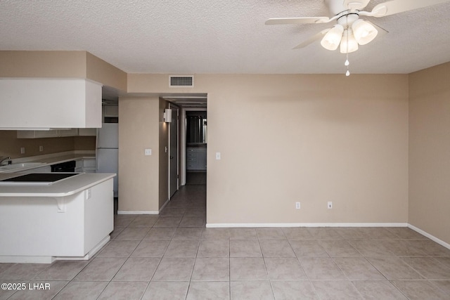 kitchen featuring light tile patterned floors, ceiling fan, fridge, a textured ceiling, and black electric cooktop